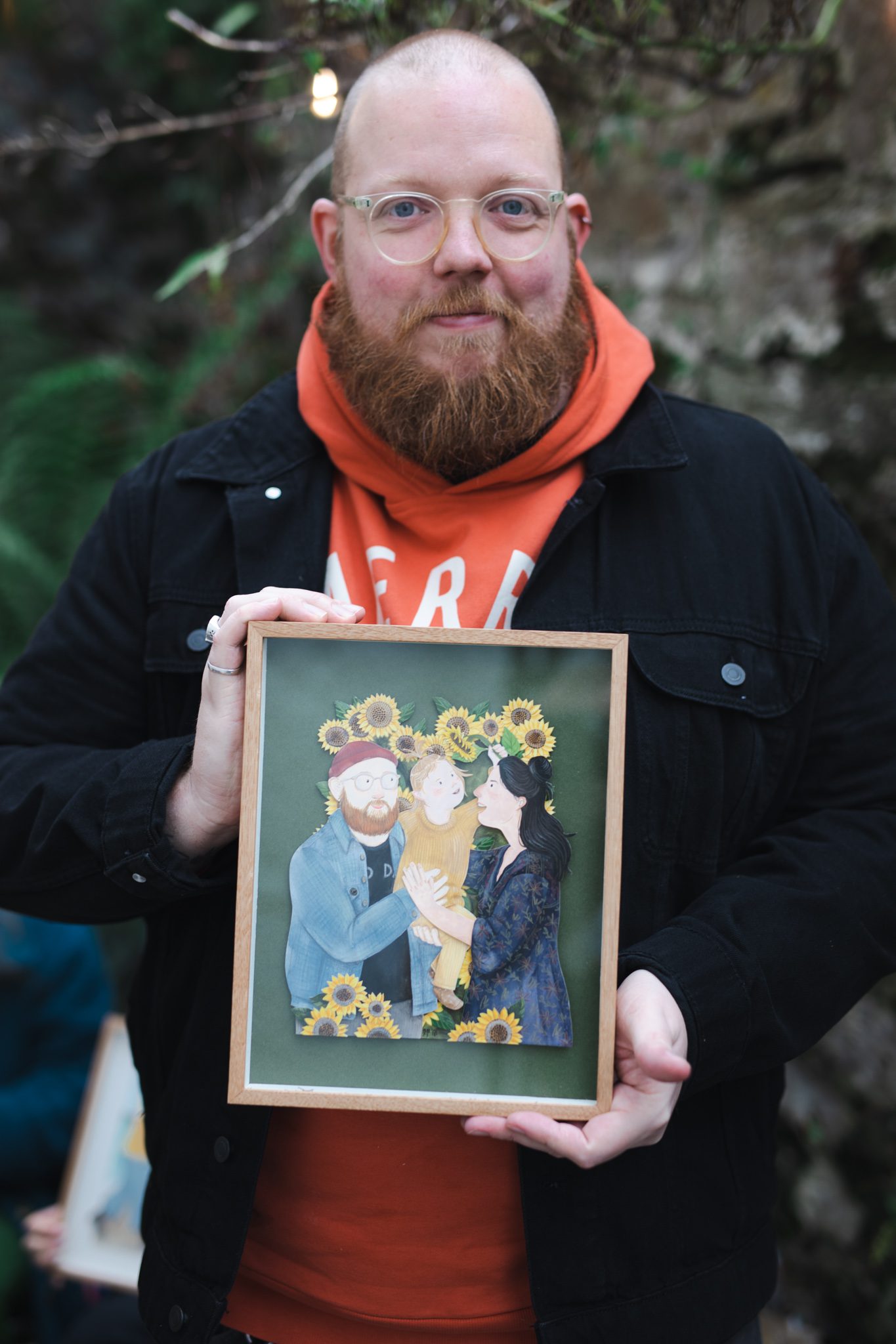 Chris holding portrait by artist Bex Bourne