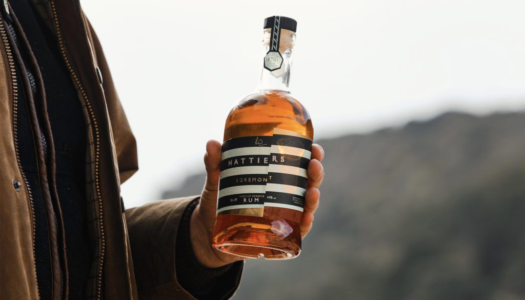 Man holding bottle of Hattier's Rum label designed by Kingdom & Sparrow